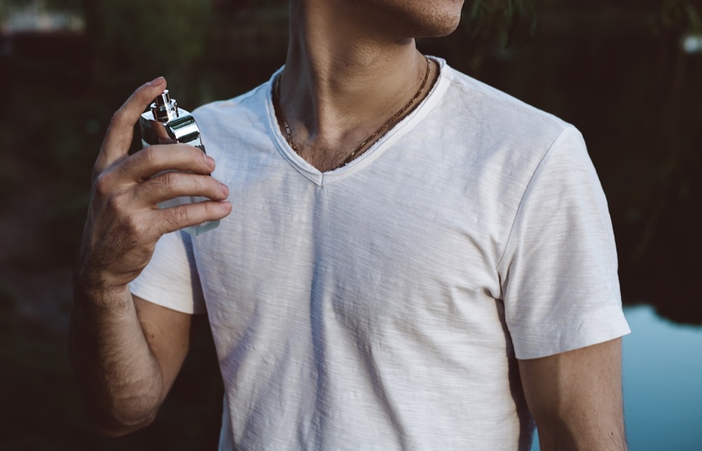 man in a white tee shirt spraying cologne