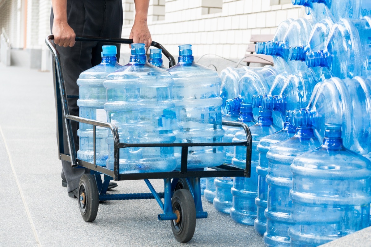 Man pushing a cart full of gallons of water