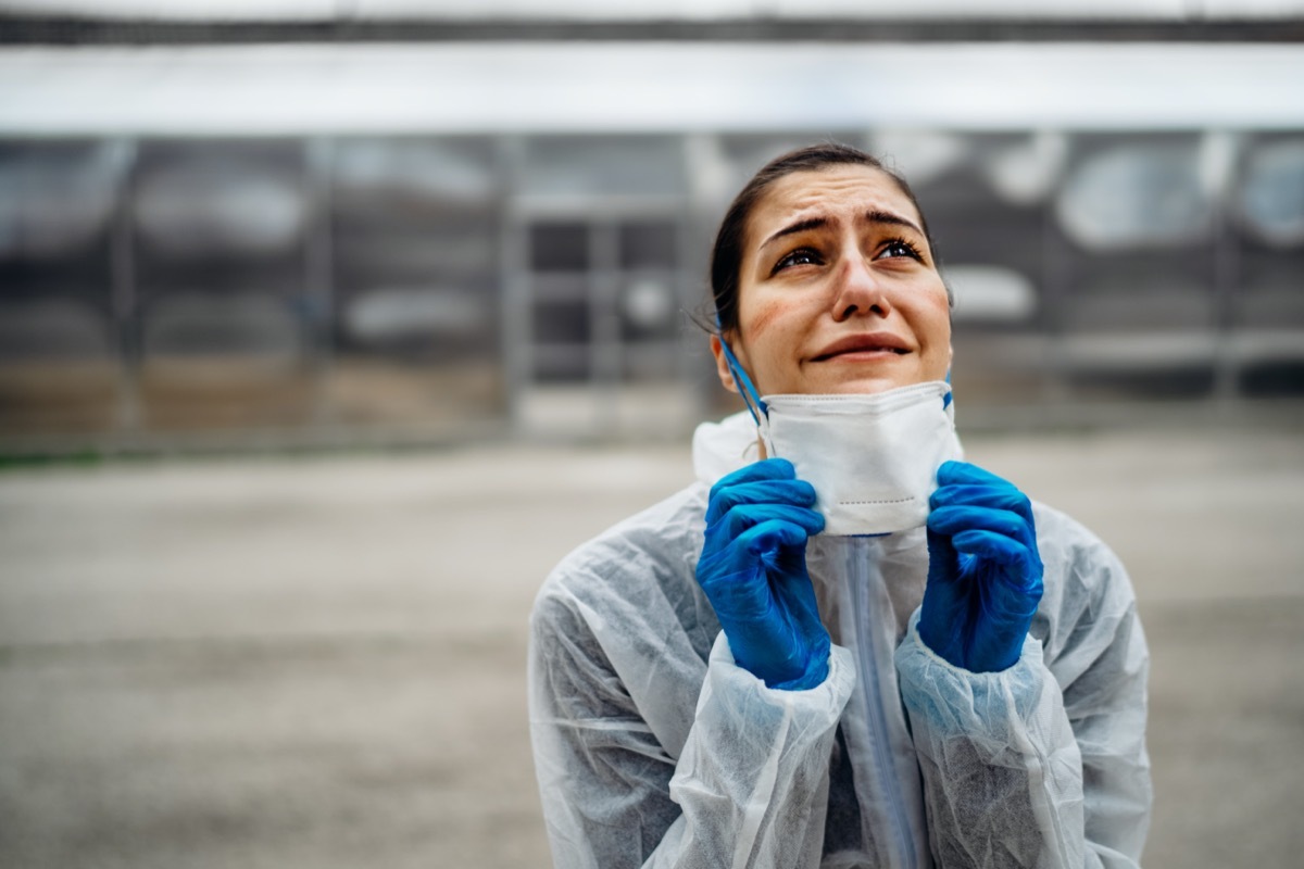 Exhausted crying doctor/nurse in coronavirus protective gear N95 mask