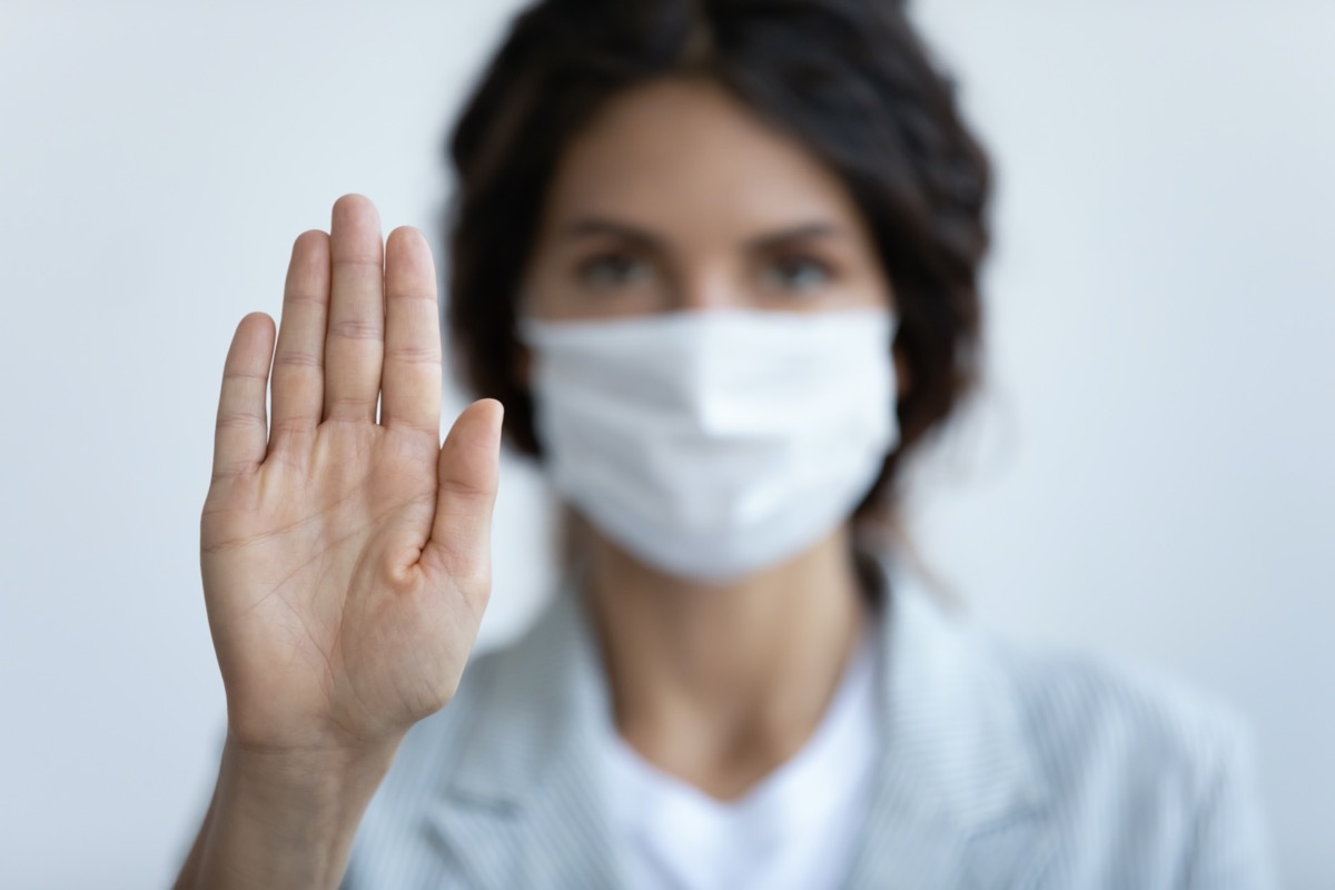 woman in mask focus on stretched hand as symbol of keep distance avoid communication