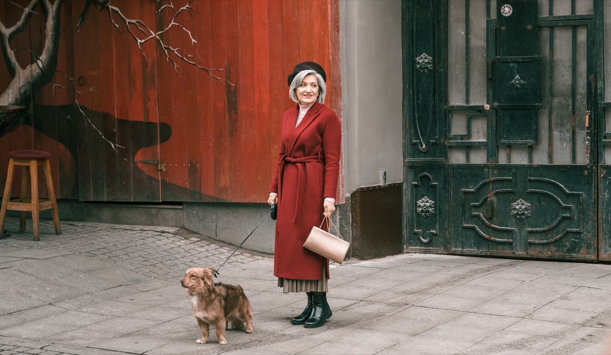 woman walking with lovely dog pet in red coat