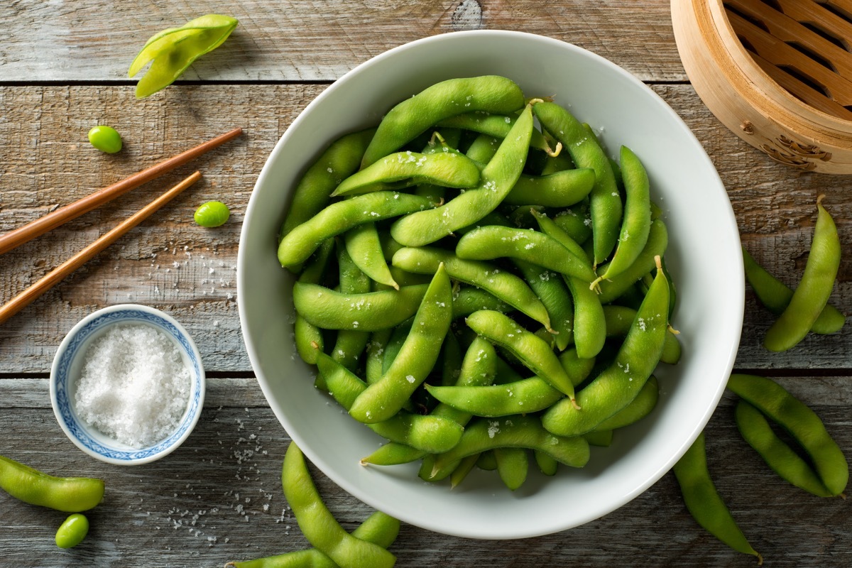 Fresh steamed edamame sprinkled with sea salt on a rustic tabletop.