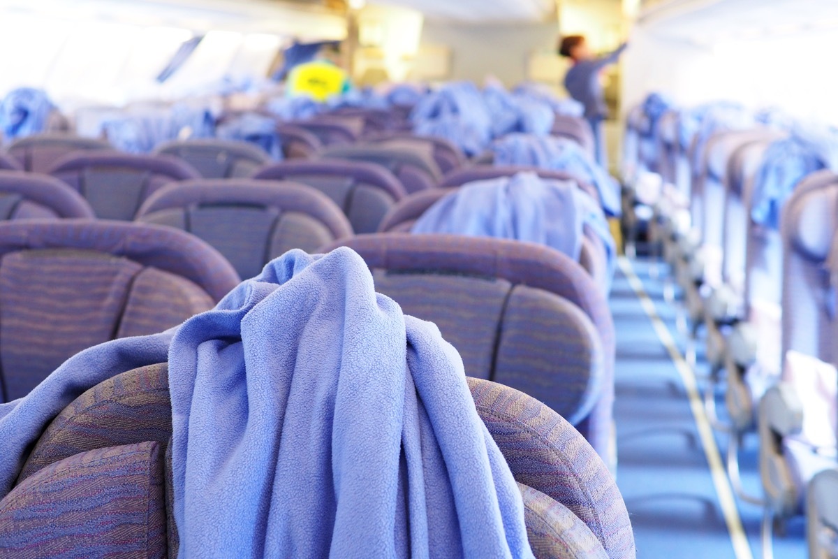 cleaning staff in the background cleaning the inside of an airplane