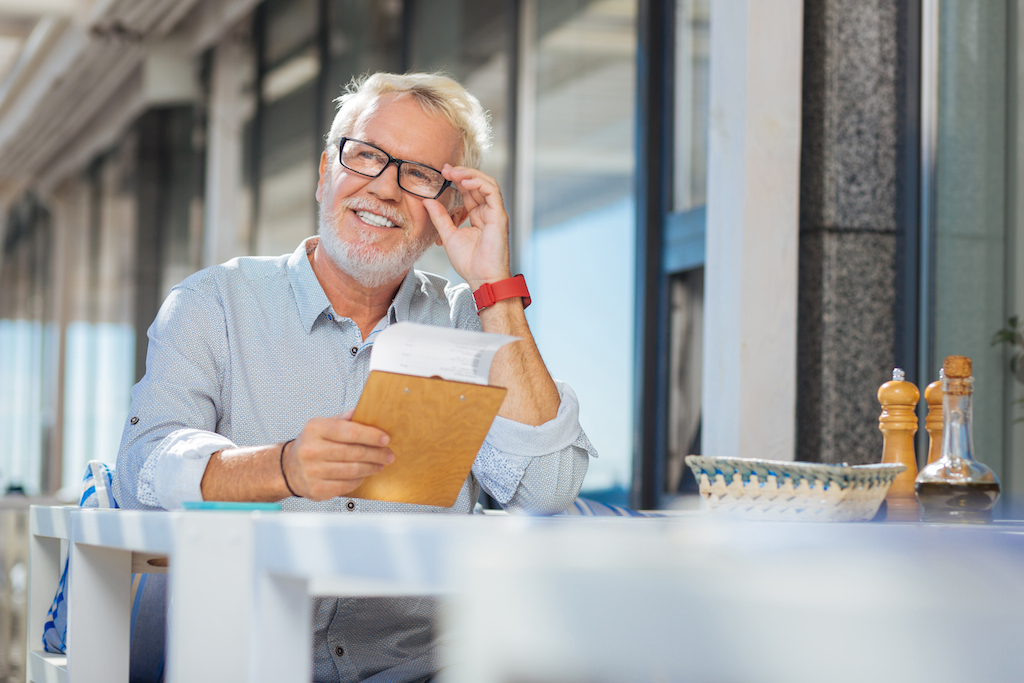 older man happily eating at a restaurant table by himself, single after 40