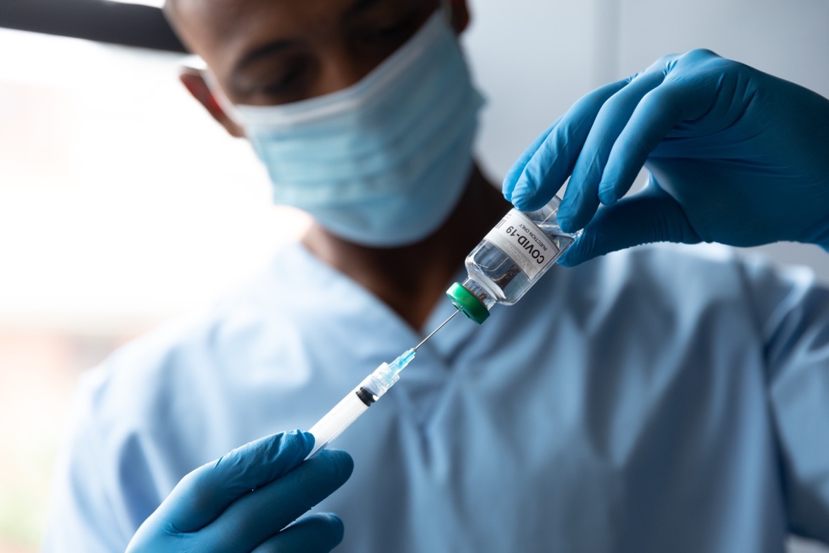 male doctor holding covid-19 vaccination wearing face mask. medicine healthcare professional during covid 19 coronavirus pandemic.