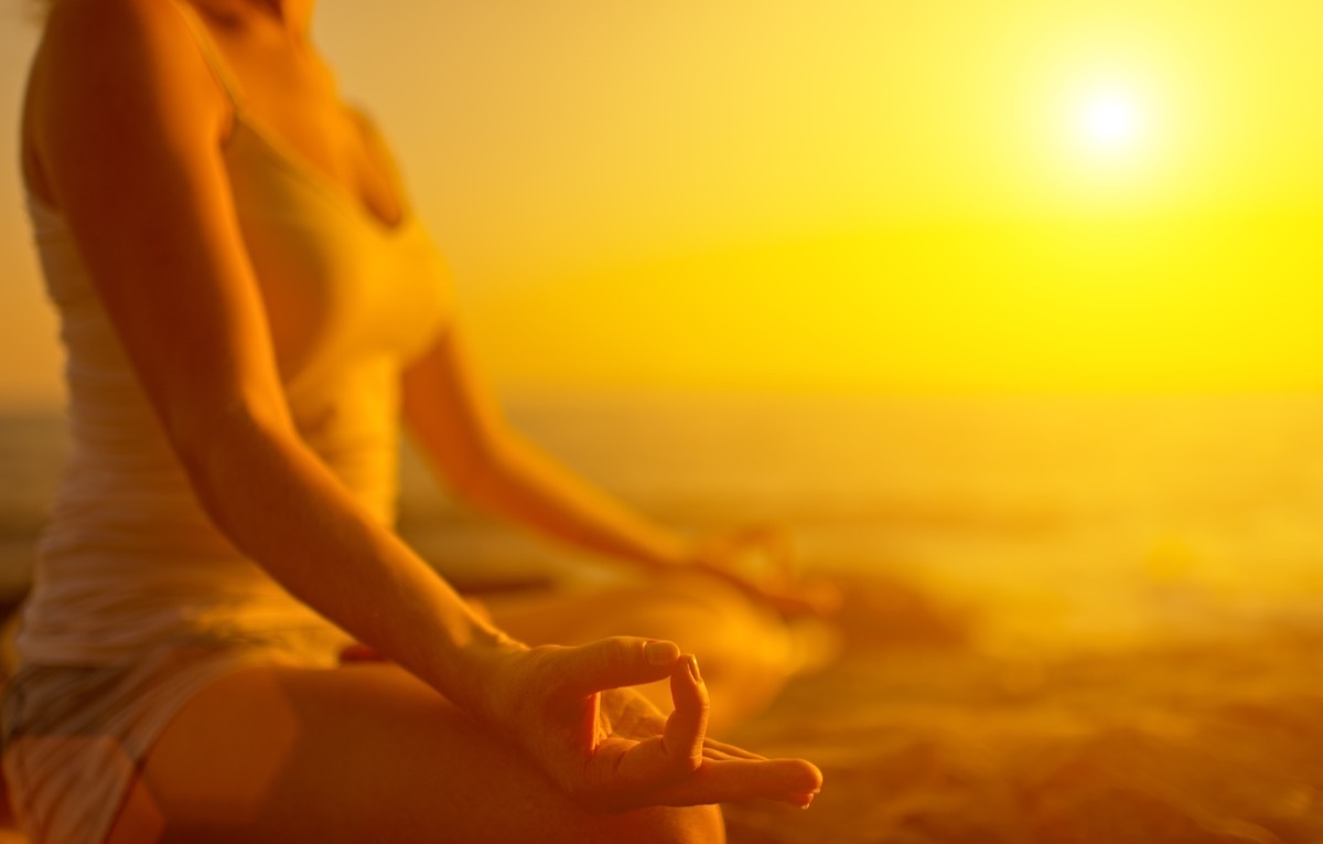 woman meditating at sunset