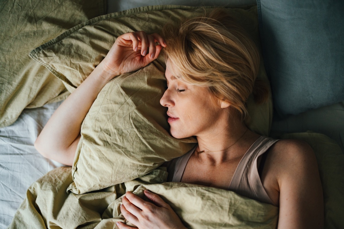 Top view of a woman sleeping in bed. She looks peaceful and fast asleep.