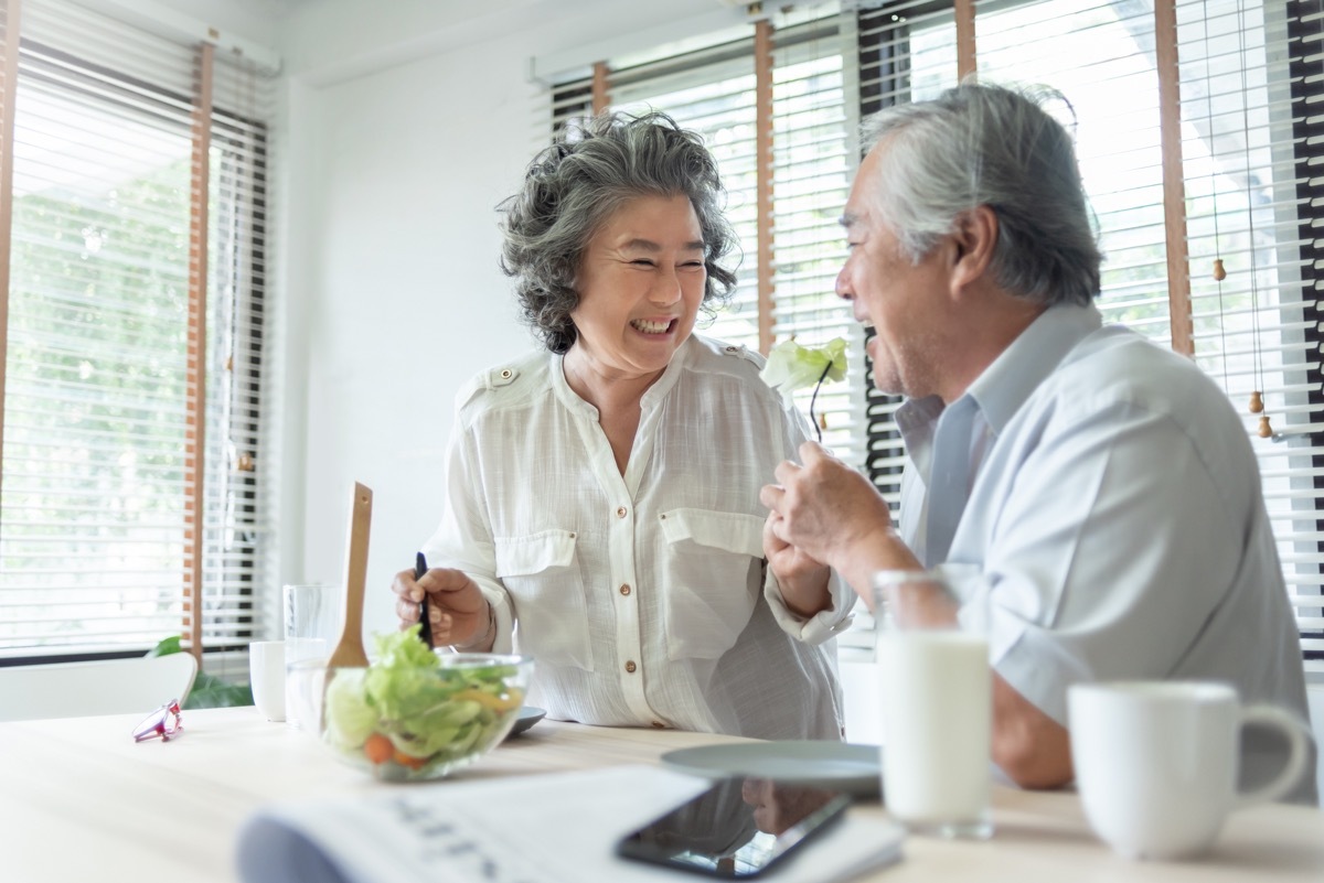 Happy Senior adult couple eating healthy salad together. Lovely Grandmother feeding to her Grandfather. Lover, Retirement, Wellness. Be Healthy