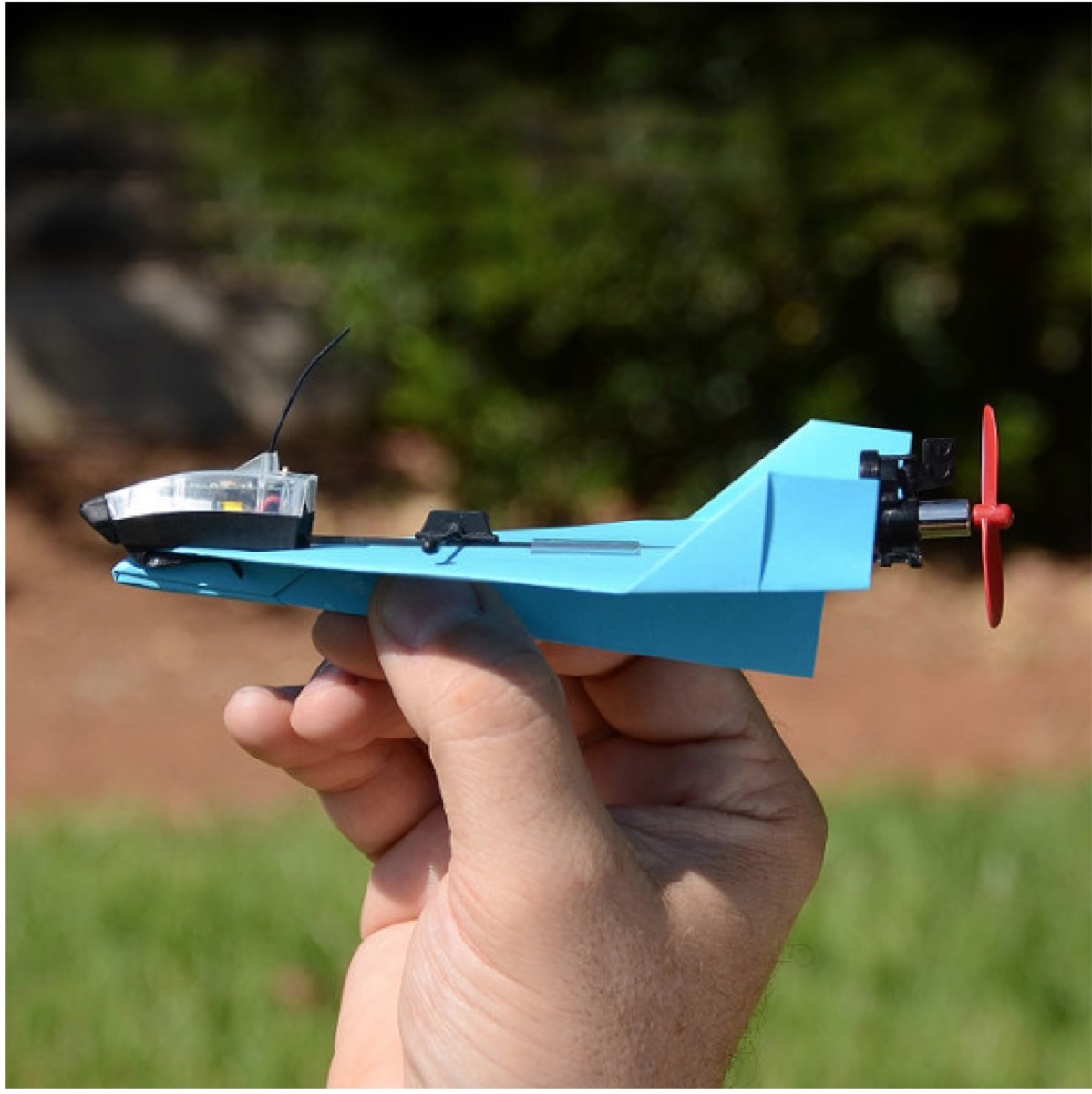 white hand holding blue smartphone controlled paper airplane