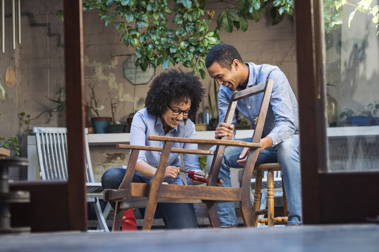 Smiling young couple working together to restore a chair