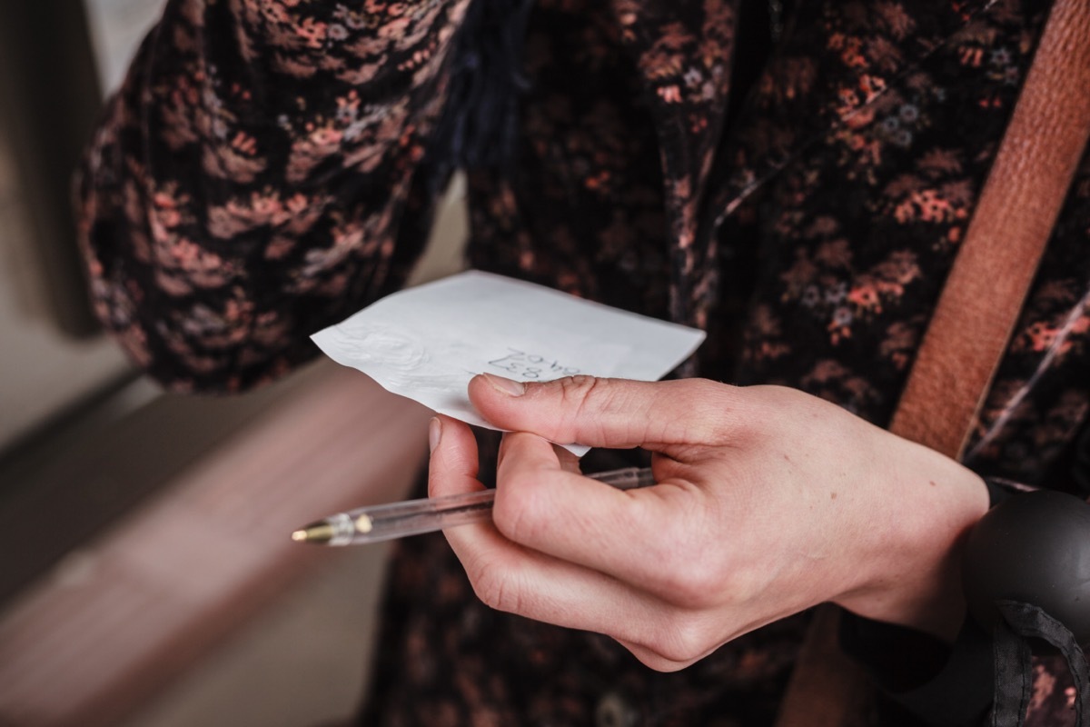 woman is holding a note with a phone number written on it.