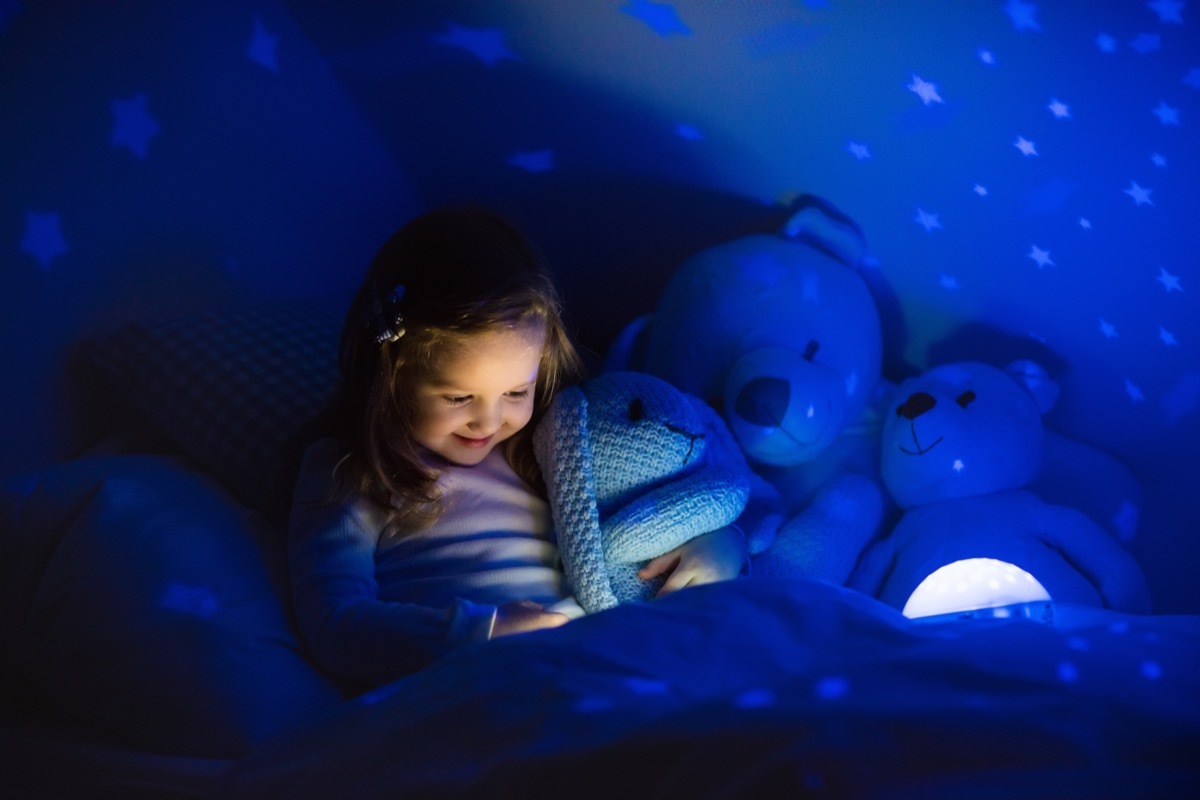 little girl using night light in bed