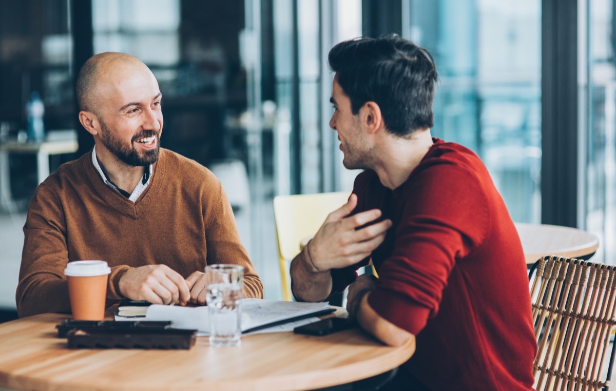 Two male friends talking and having a conversation in a coffee shop