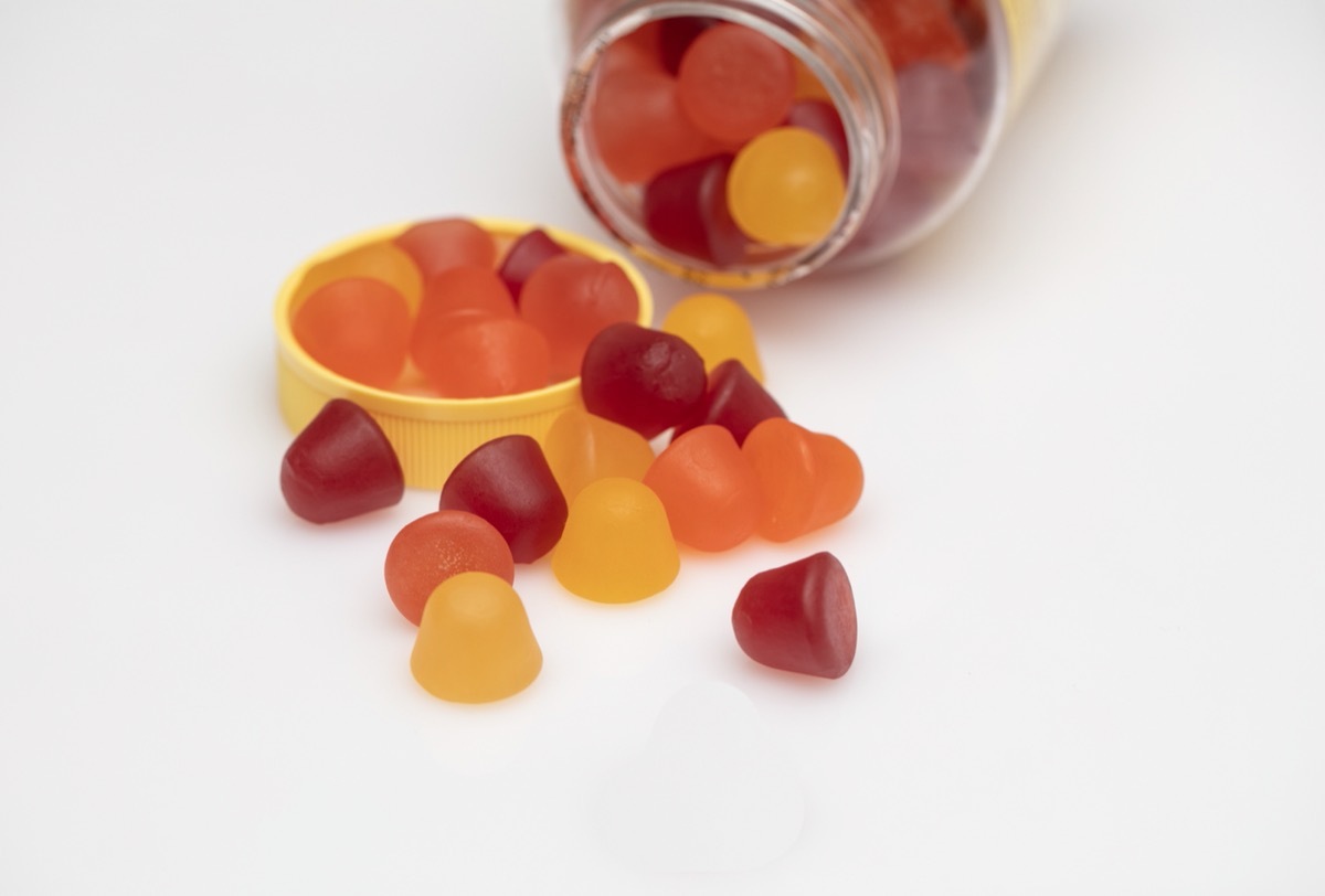 gummy vitamins being poured out of a bottle onto white surface