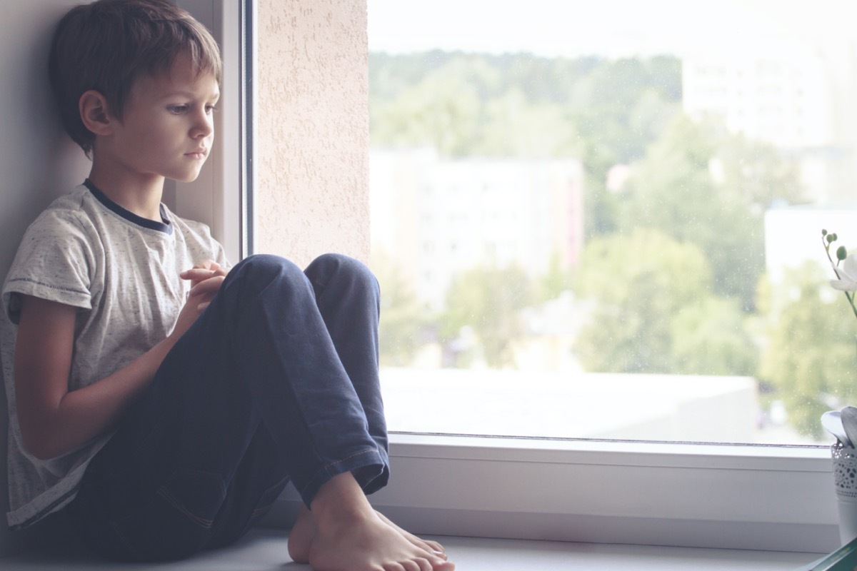 sad child sitting by a window