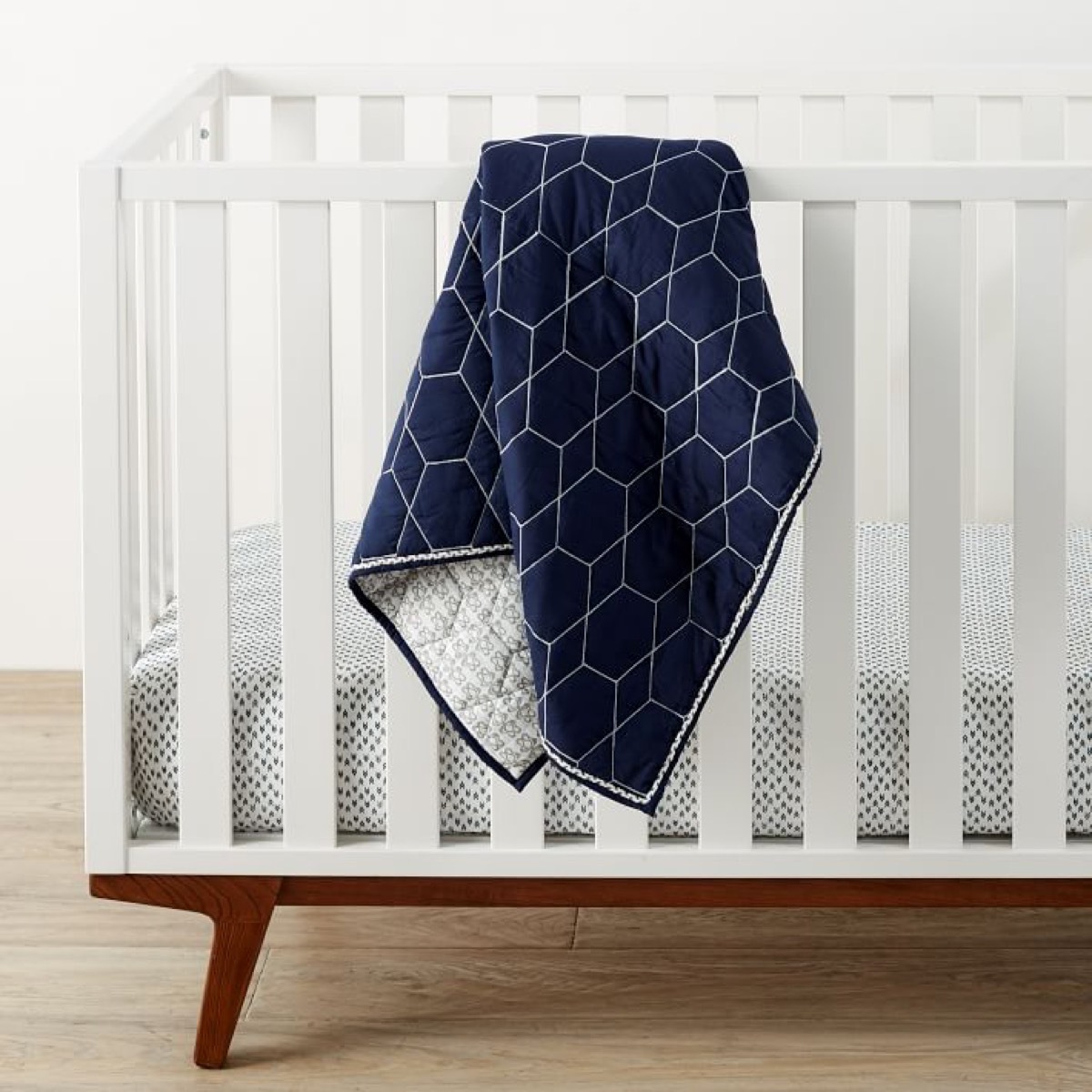 Geometric toddler quilt draped over crib