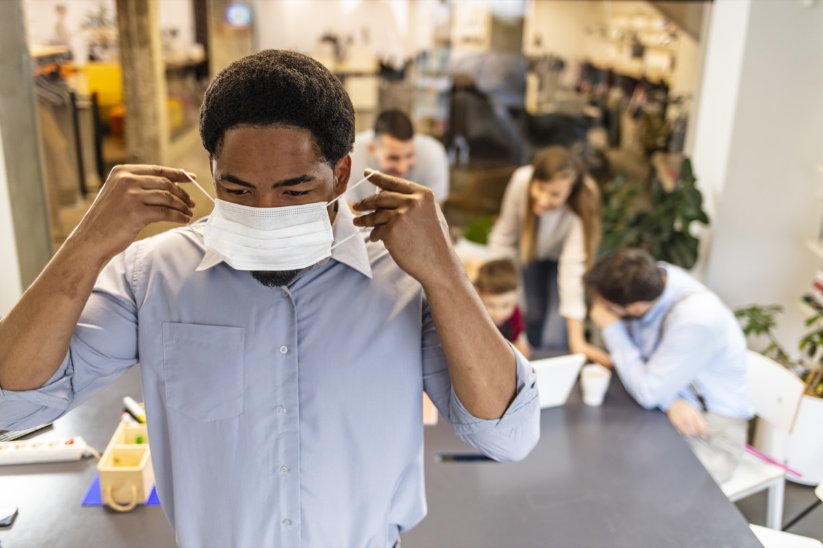 Serious businesswoman in mask in working environment.