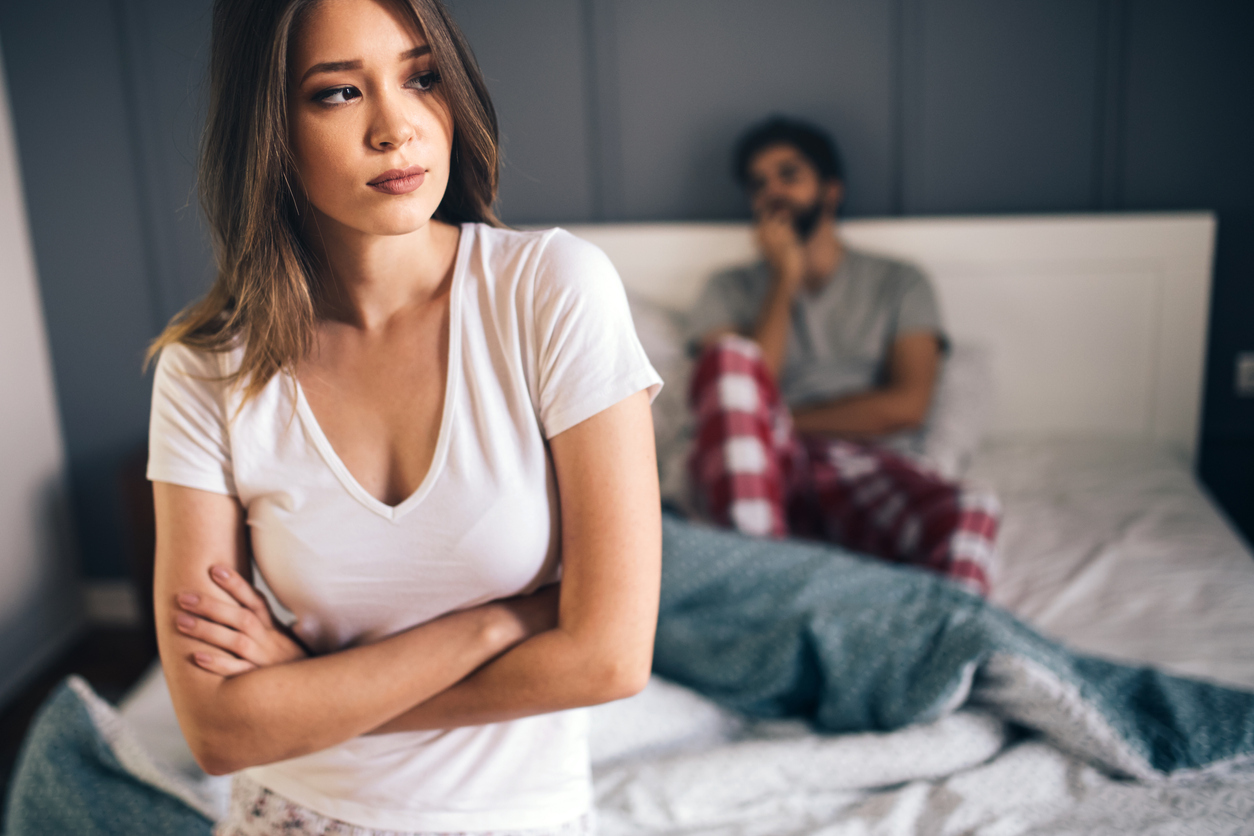 A young heterosexual couple having an argument in bed