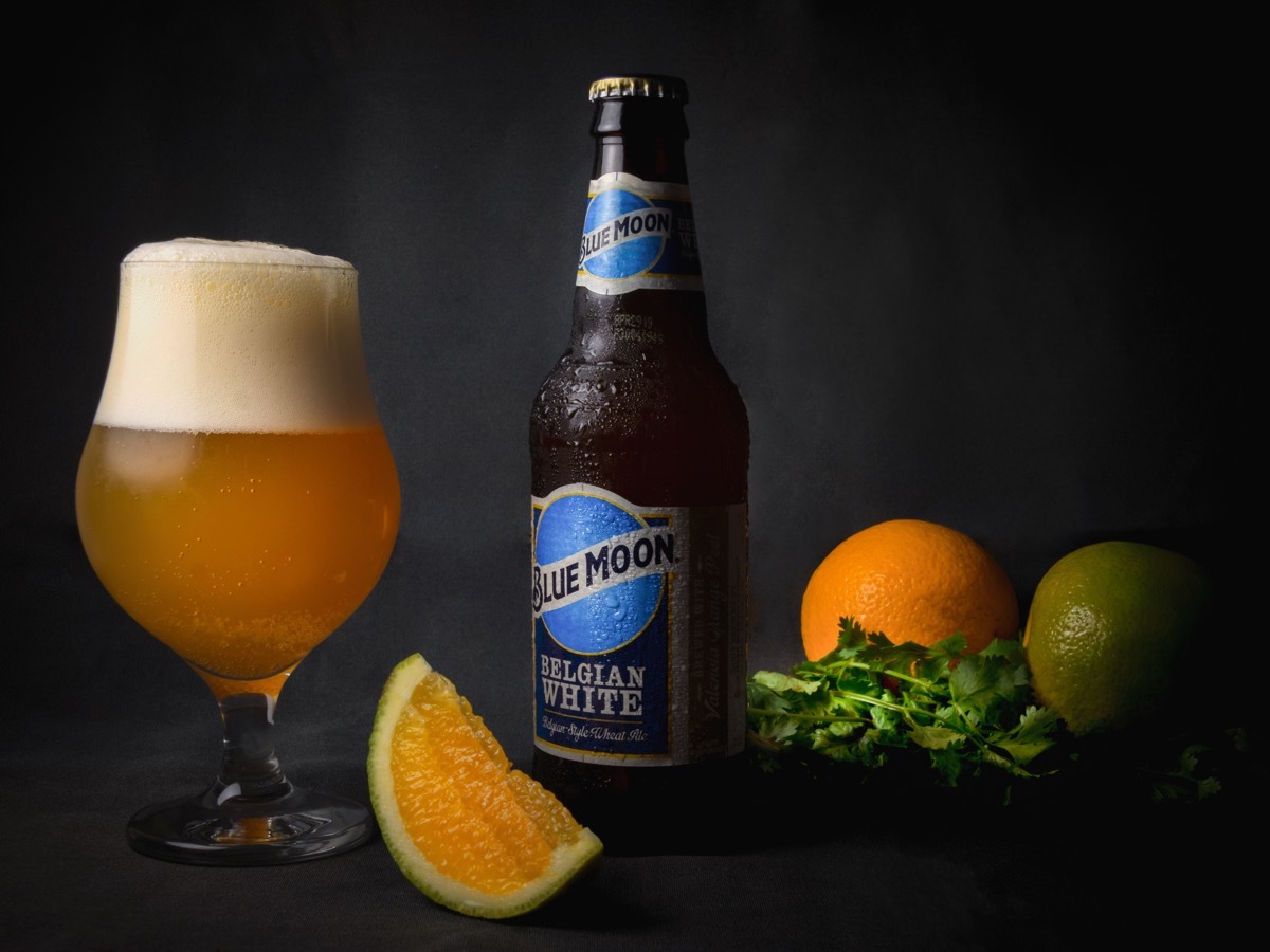 bottle of blue moon next to orange, glass