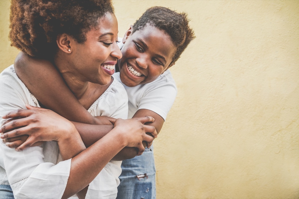 Son hugging mother from behind and laughing