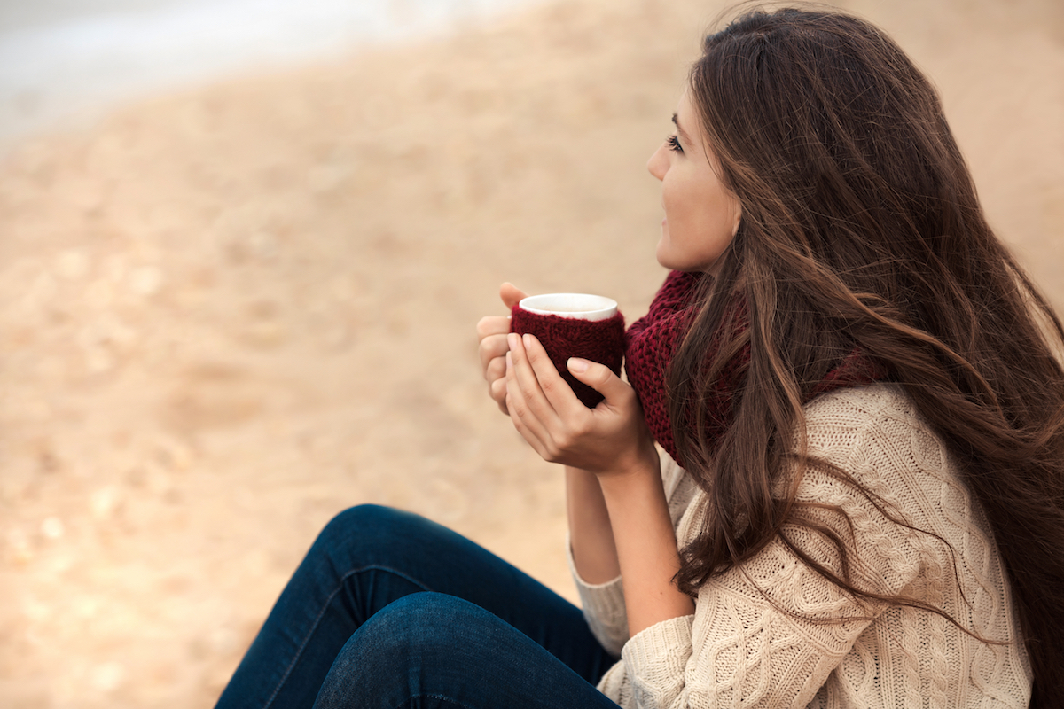 Woman drinking coffee on the beach