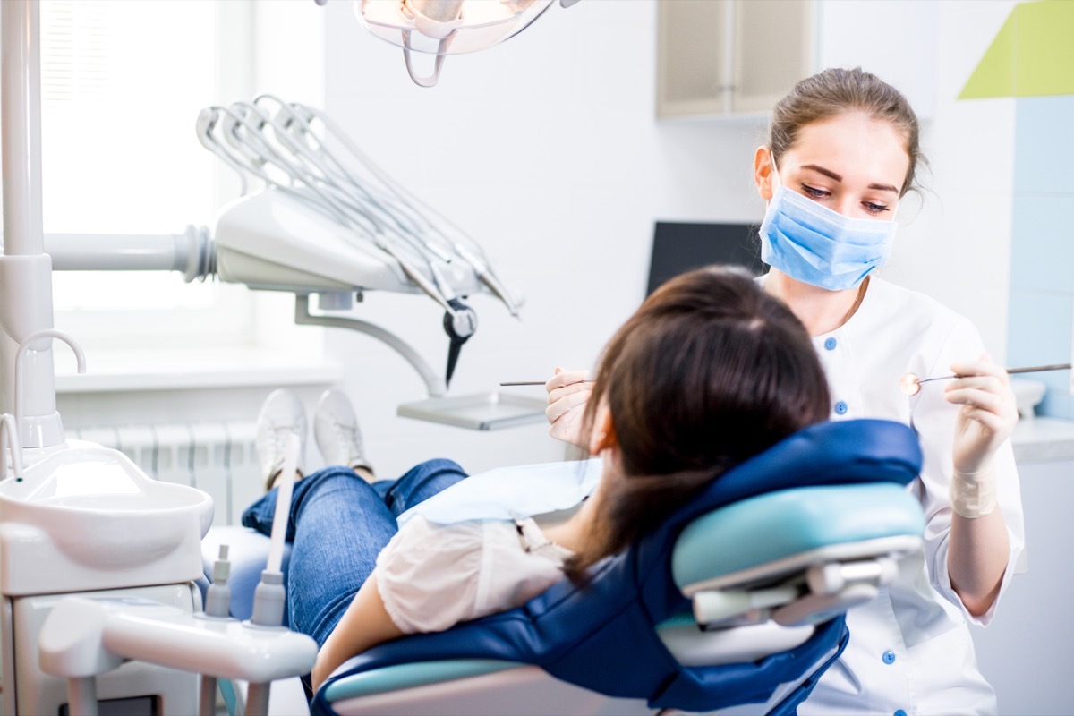 Dentist treats teeth girl lying in the dental chair