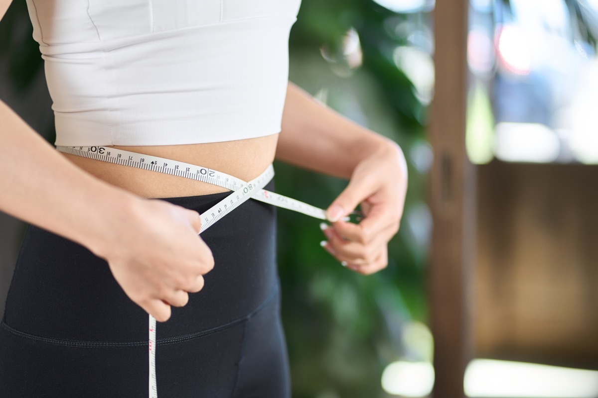 woman measuring herself for weight loss