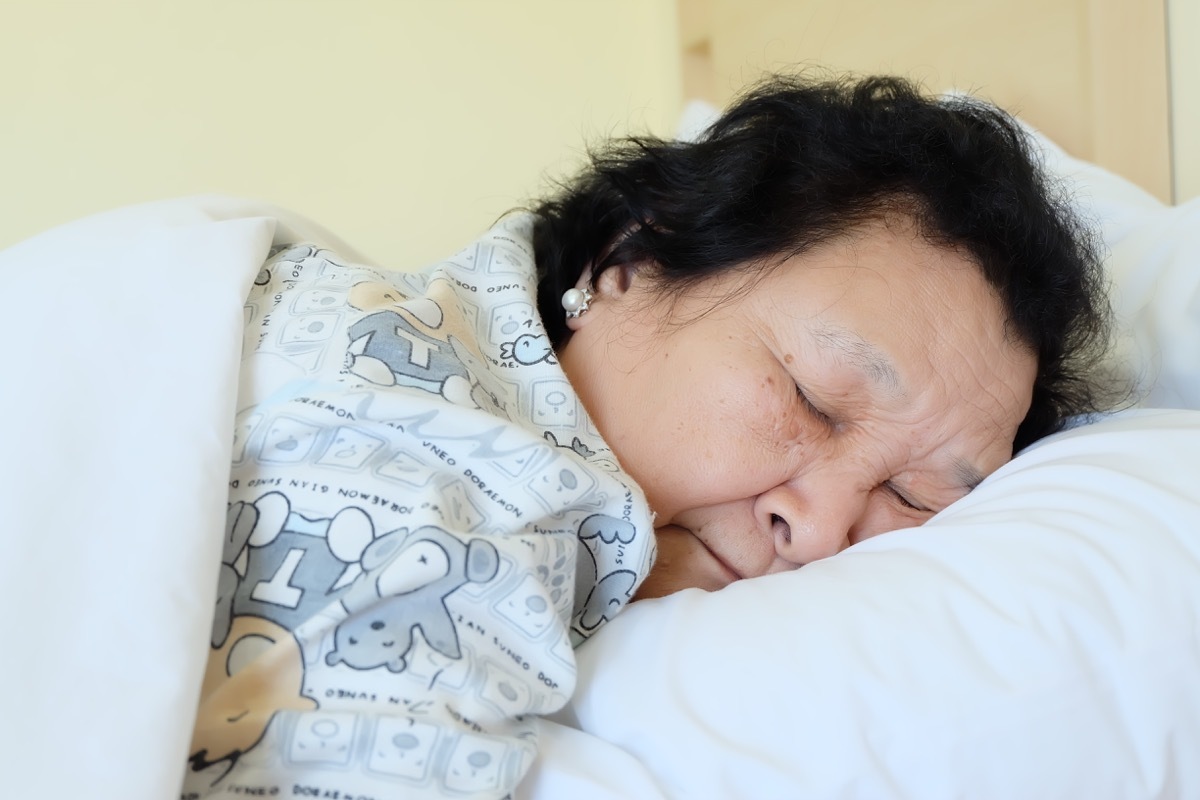 Old Asian Woman Sleeping in PJS with head on pillow