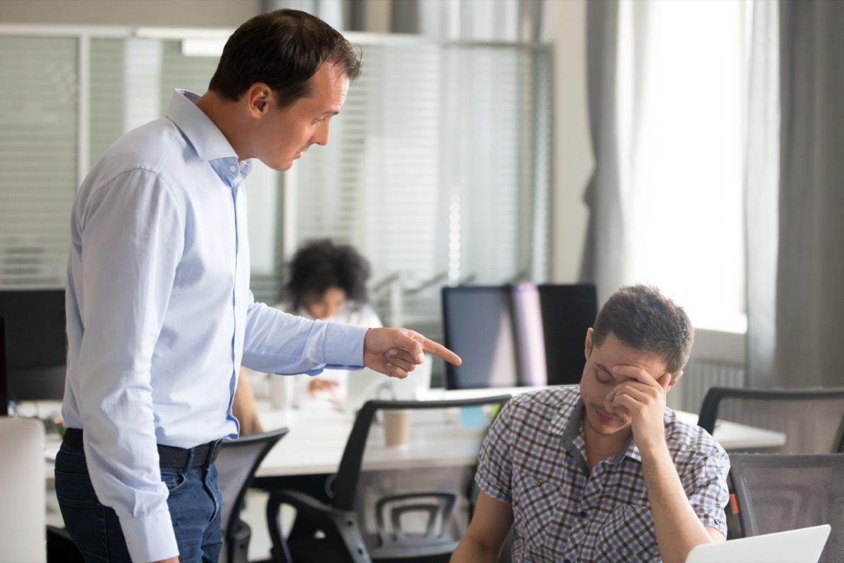 middle aged male boss yelling and pointing at employee