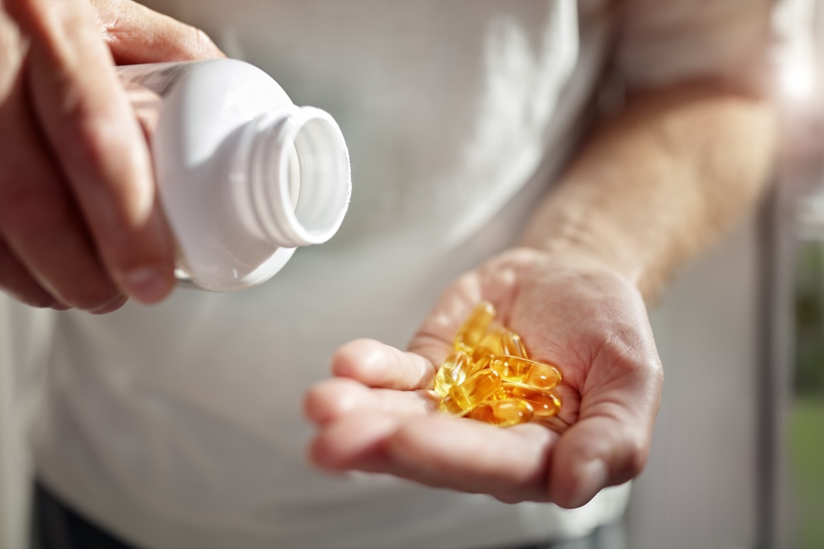 Bottle of omega 3 fish oil capsules pouring into hand