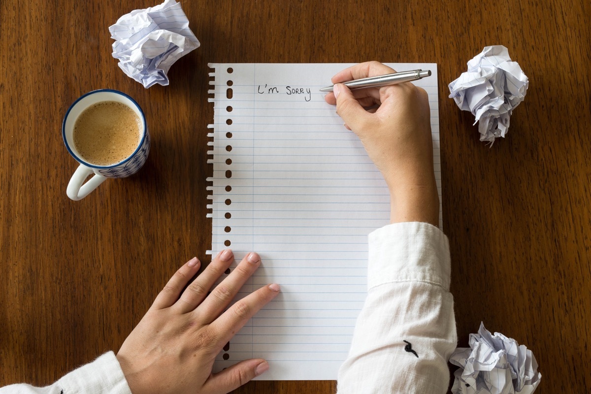 man writing 'i'm sorry' on notepad