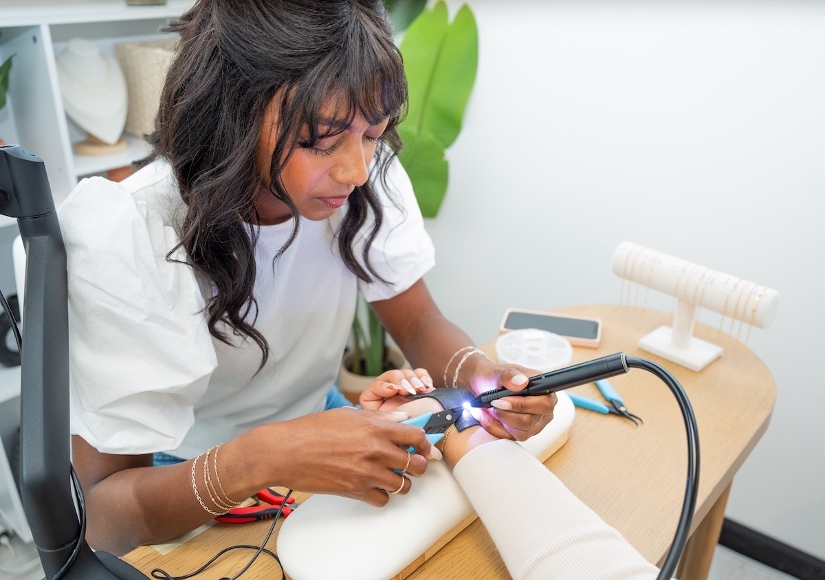 A female jeweler welding a permanent bracelet on the wrist of a client