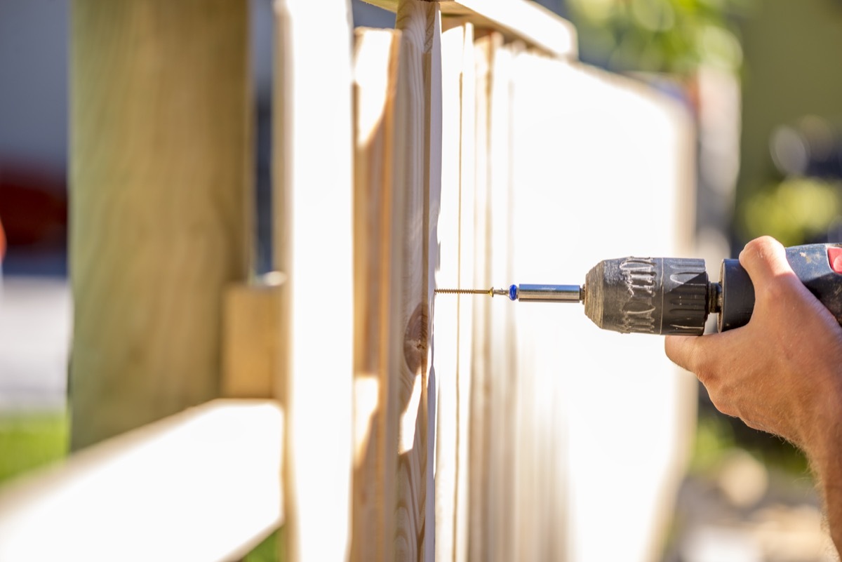 man putting a wooden fence up outside his home