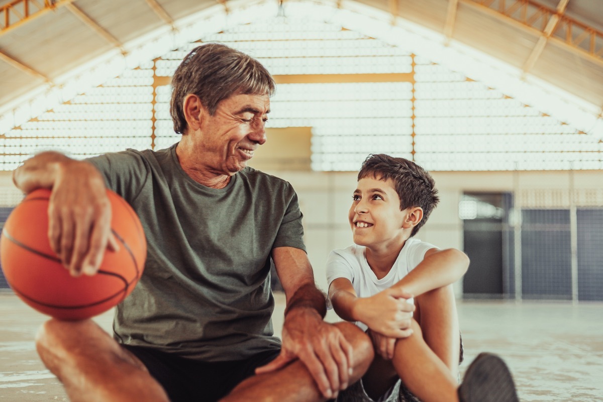 Latin grandfather and grandson playing basketball on the court