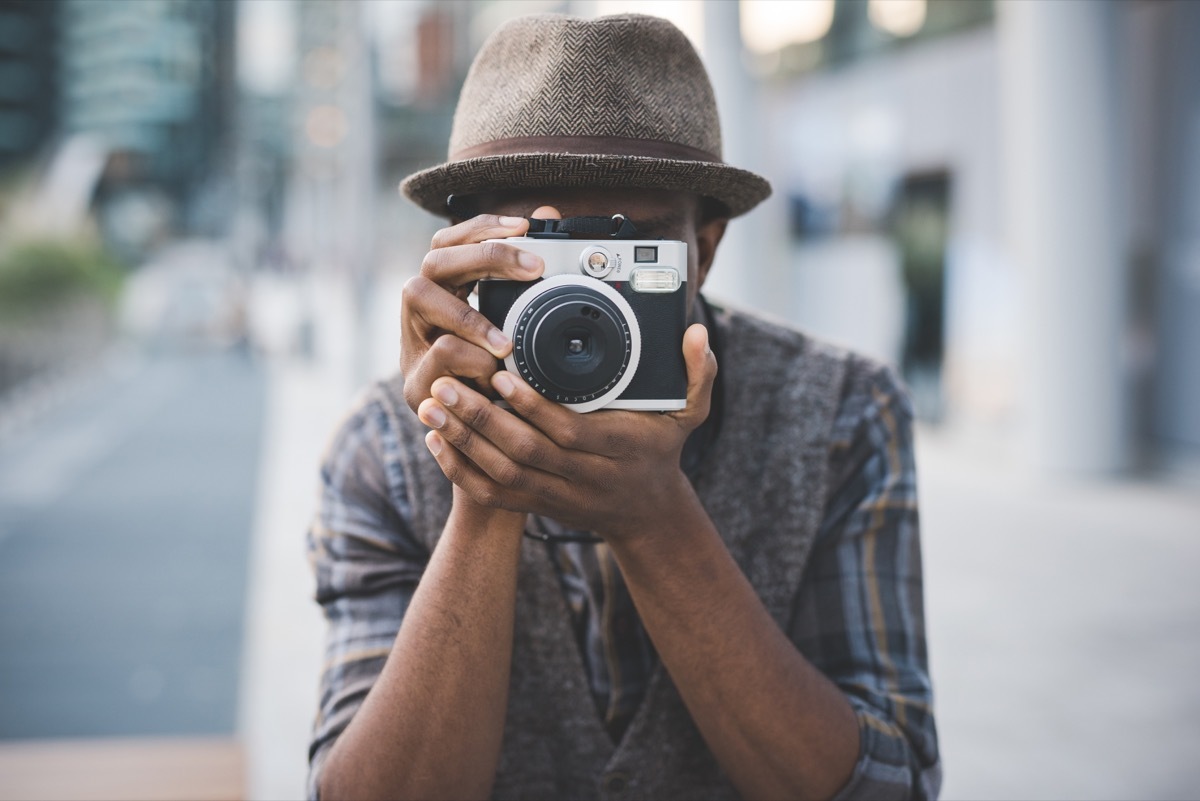 Half length of young beautiful afro black man outdoor in the city holding instant camera, shooting - photography, creative, artist concept - Image