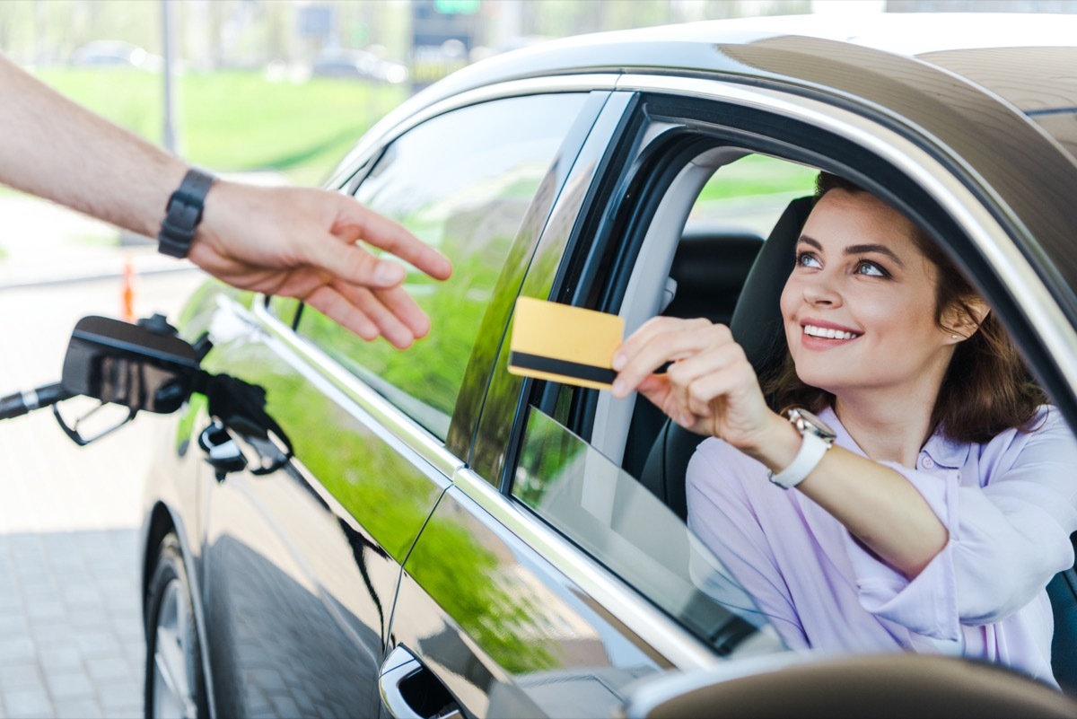 woman gives her credit card to a gas station attendant