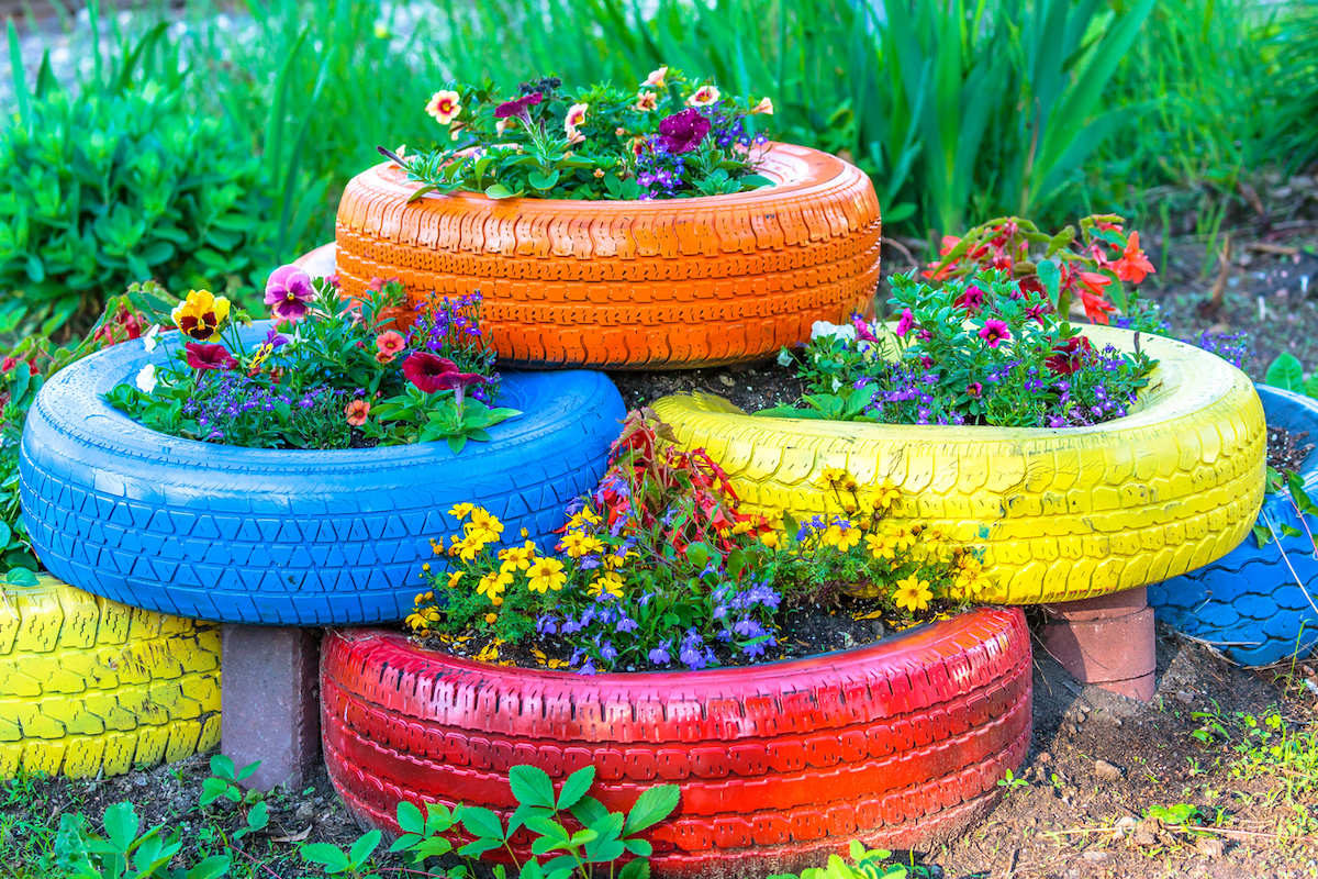 Old tires that are painted in assorted colors and used for a flower planter.