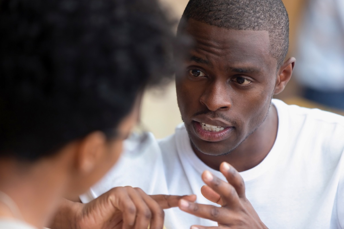 black man having a serious conversation with a woman, whose head is to the camera