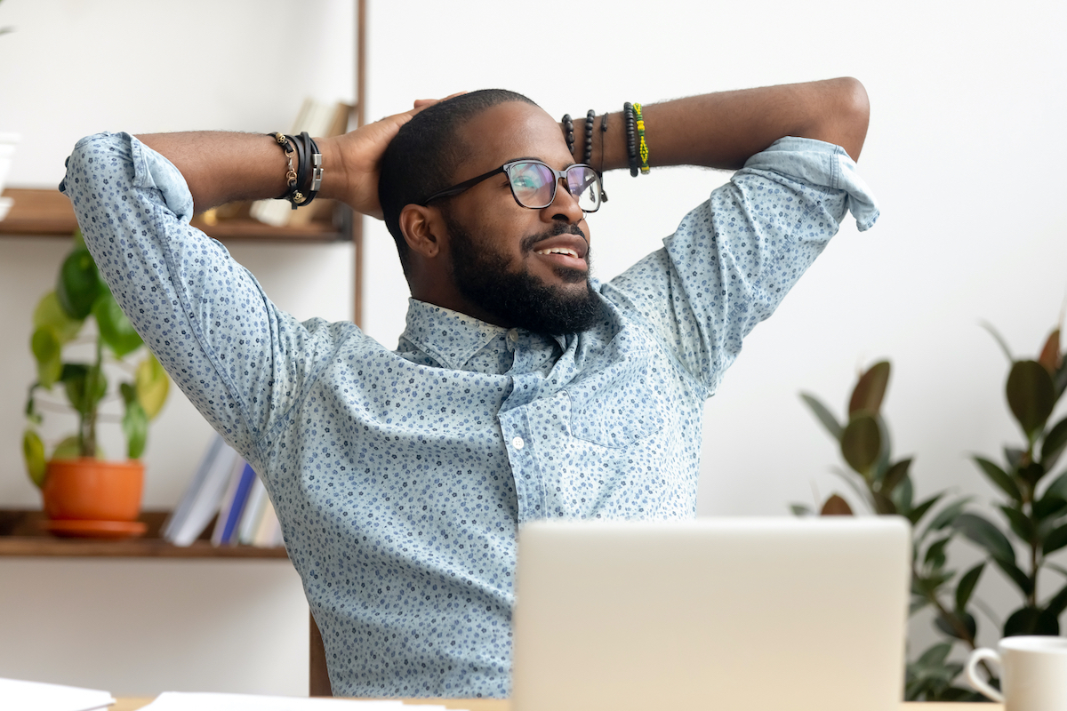 Calm african american business man take break at workplace relaxing finished work, happy black professional employee enjoy success rest from computer feeling stress relief peace of mind sit at desk