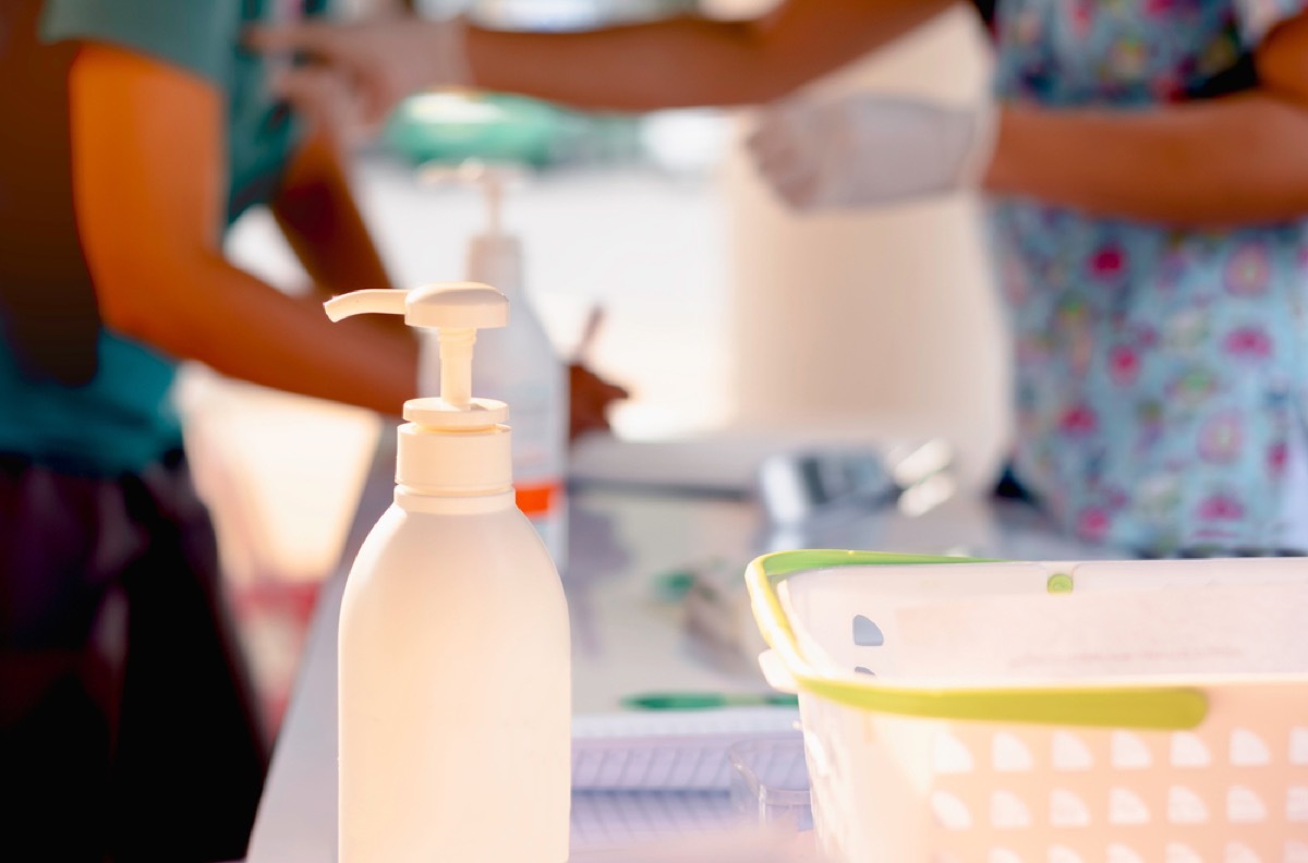 nurse in hospital in background of photo with supplies and sanitizer in the foreground