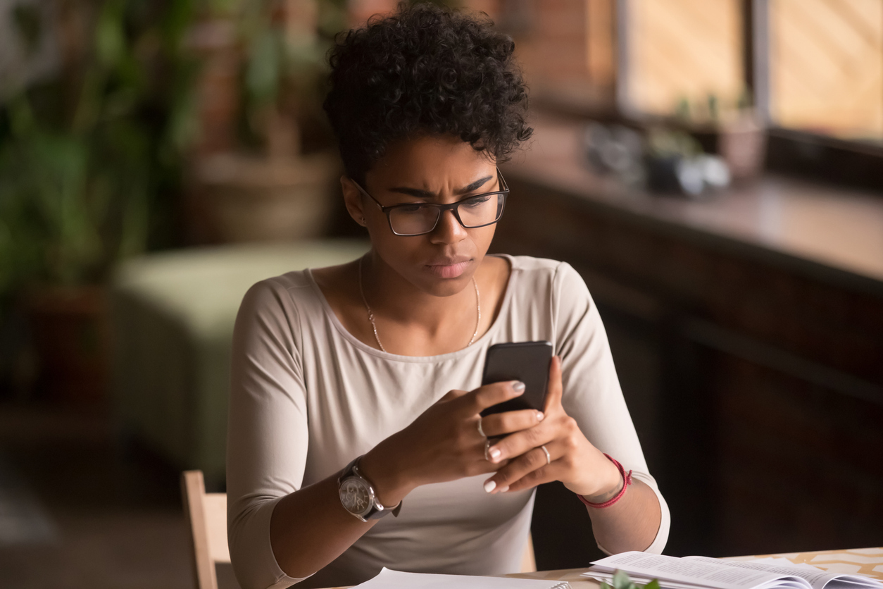 A young woman looking at her phone with a concerned look on her face