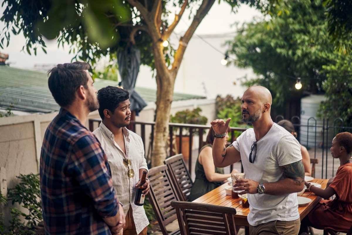 a small group of men talking outside at a party