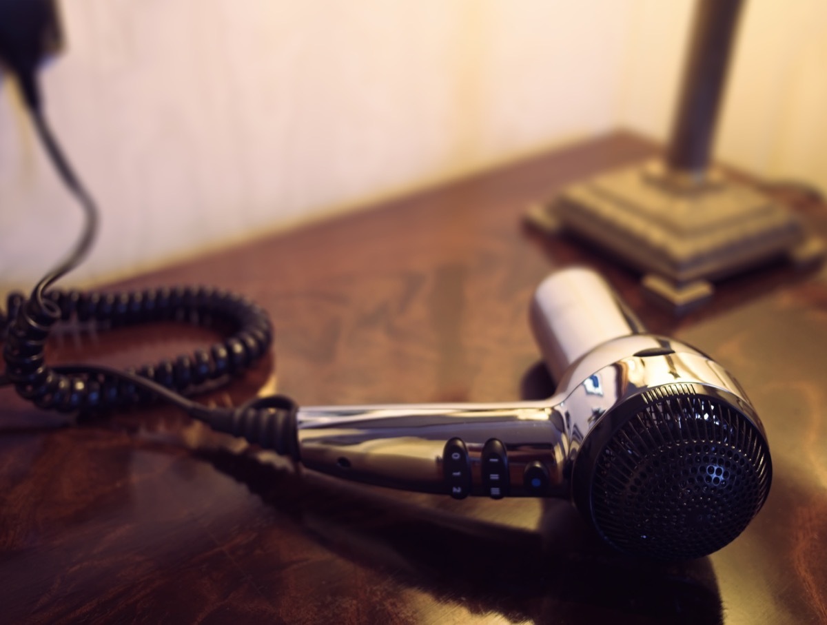 Silver hair dryer on a wooden dressing table.