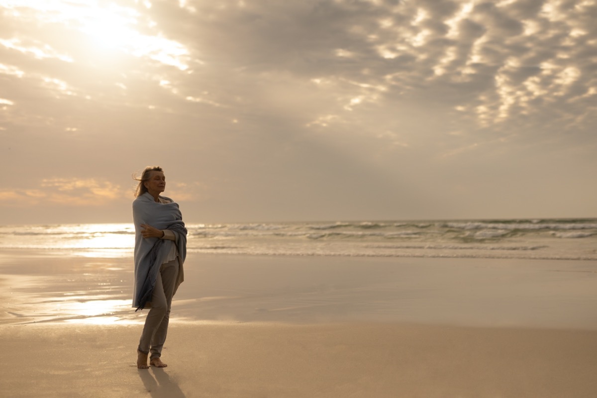 Senior woman standing alone on beach