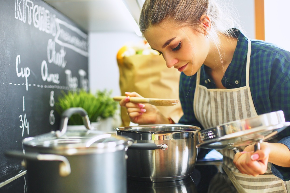 Woman Holding A Lid to a Pot with Other Pots on the Stove