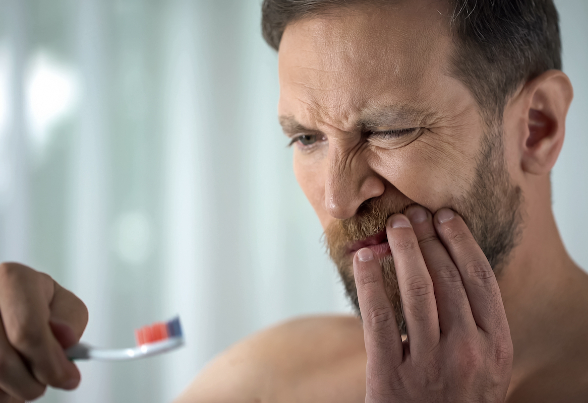 Man brushing teeth and in pain