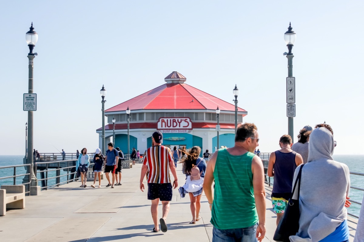 People walk on the Huntington Beach Pier, with Ruby's Diner