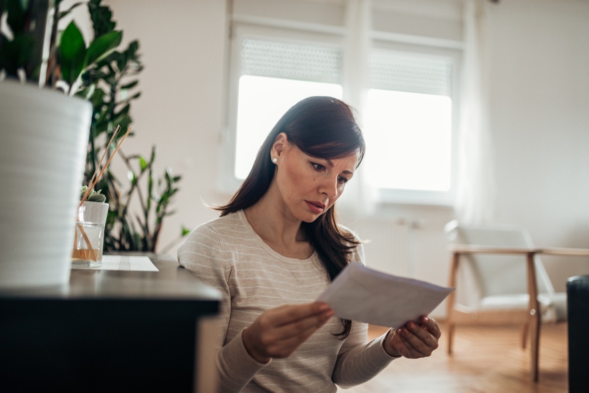 Worried woman reading a letter at home.