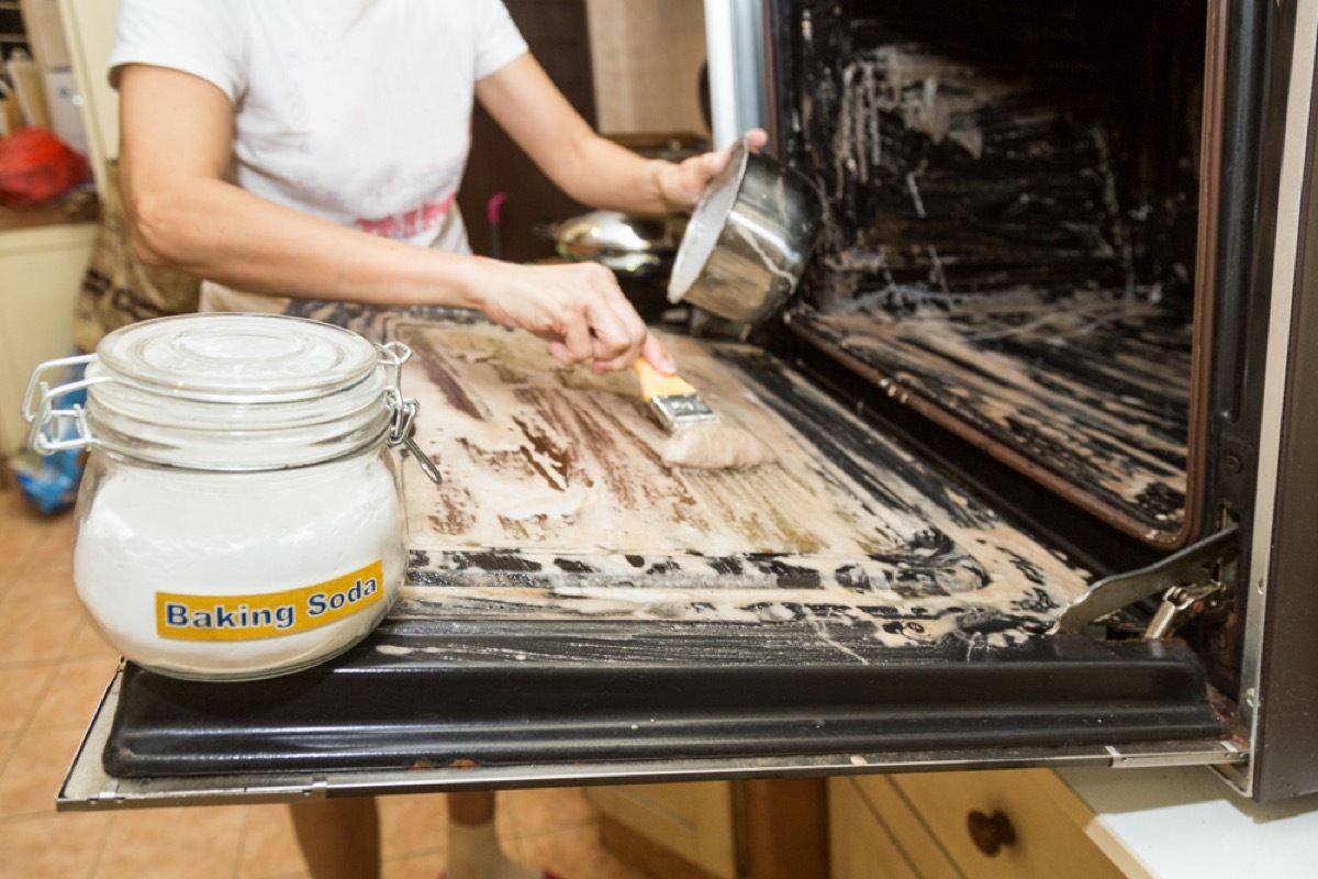 woman cleaning oven with baking soda, old school cleaning tips