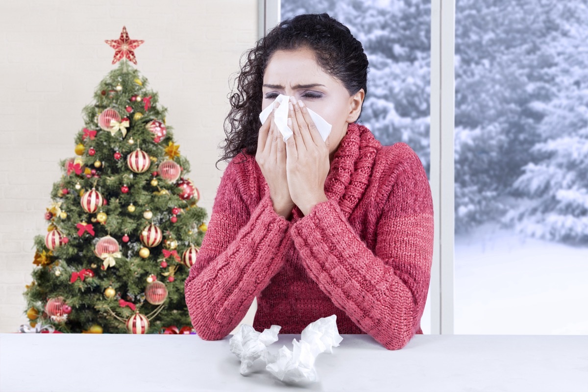 Woman blowing her nose at home